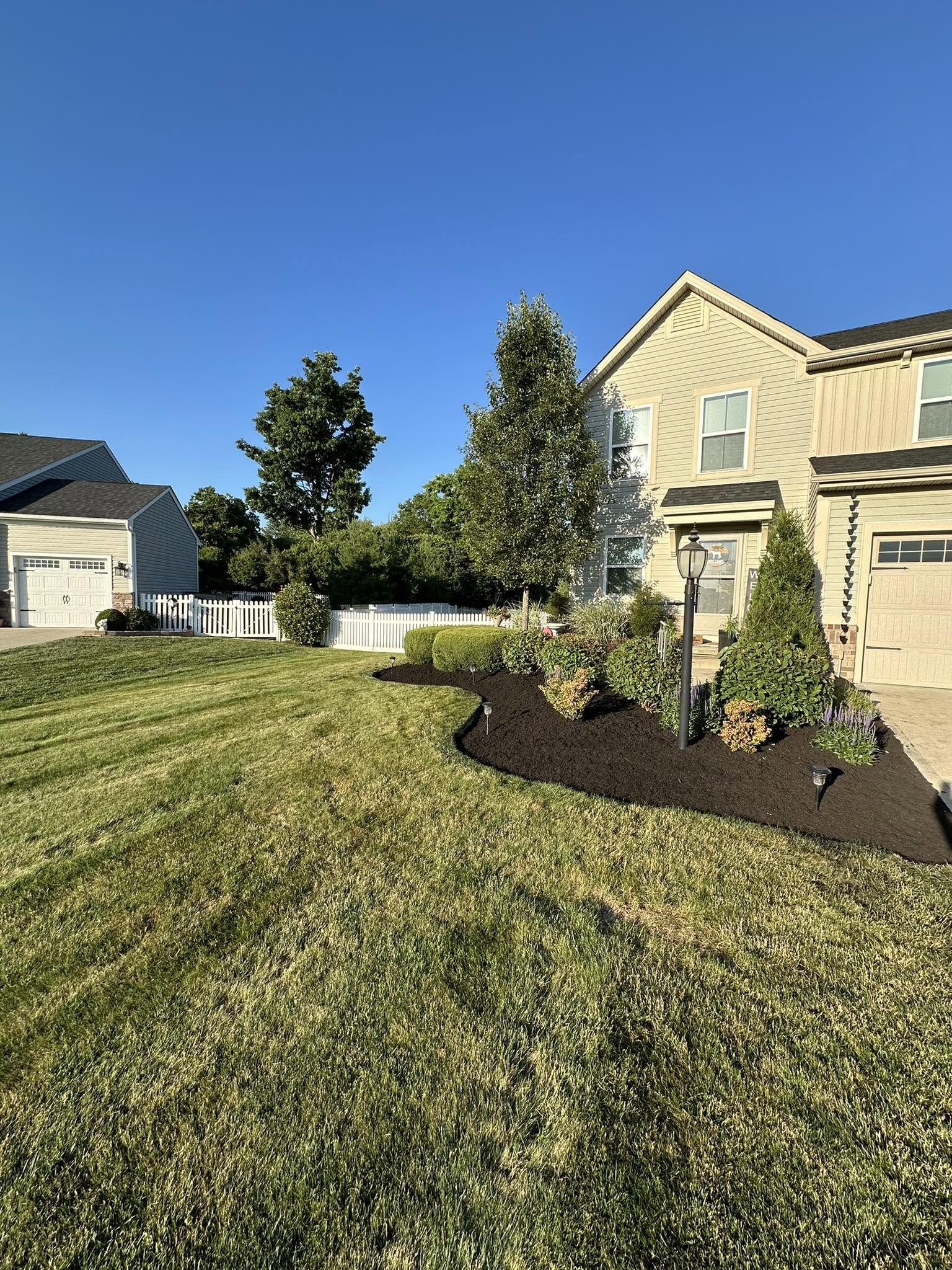 Fresh black mulch installed in a curved front yard planting bed