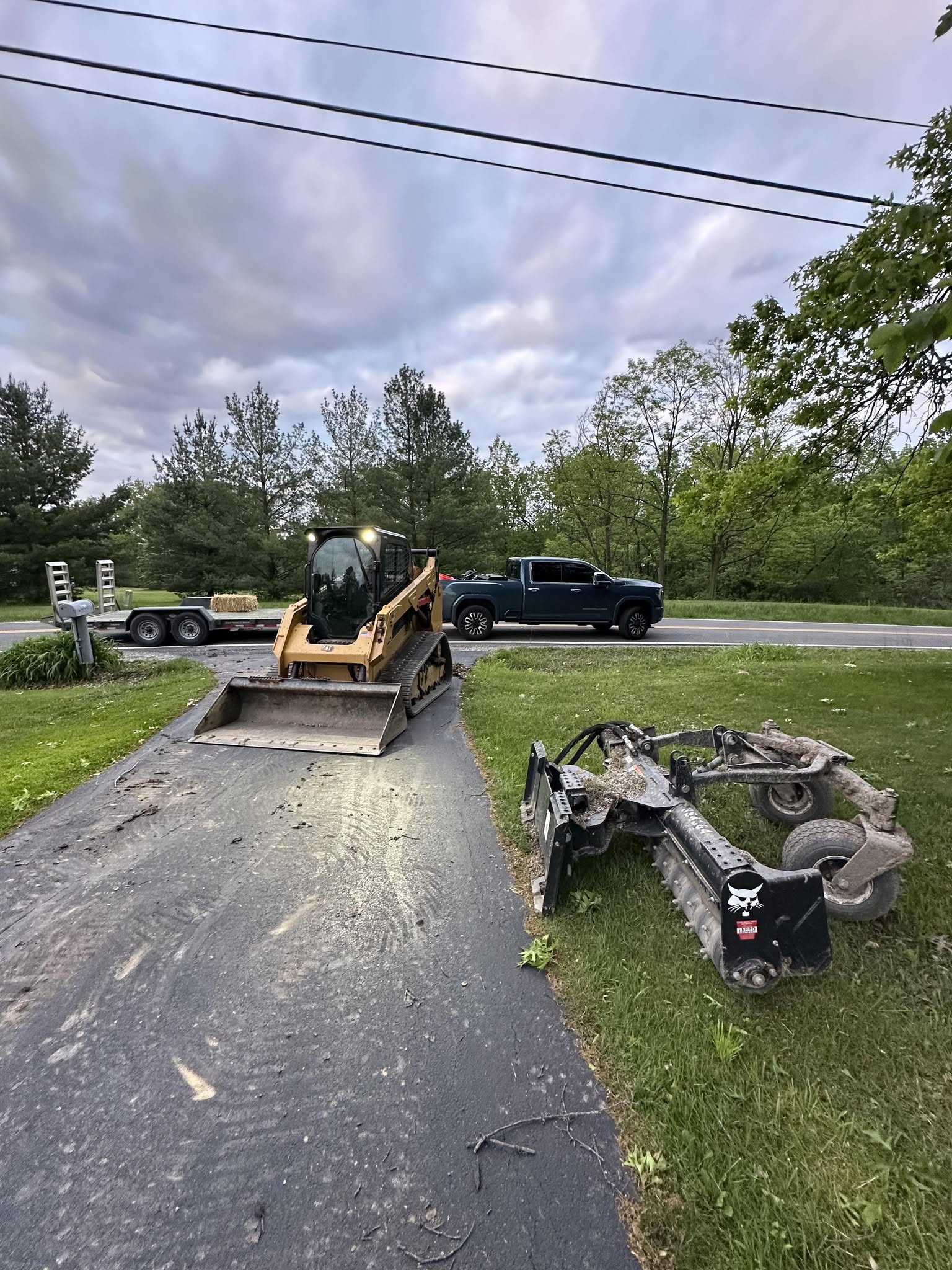 Tracked skid steer with grading and mowing attachments ready for work